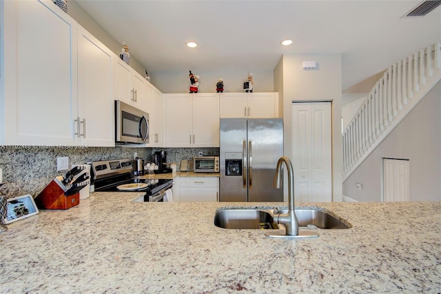 kitchen featuring light stone counters, sink, white cabinets, and appliances with stainless steel finishes