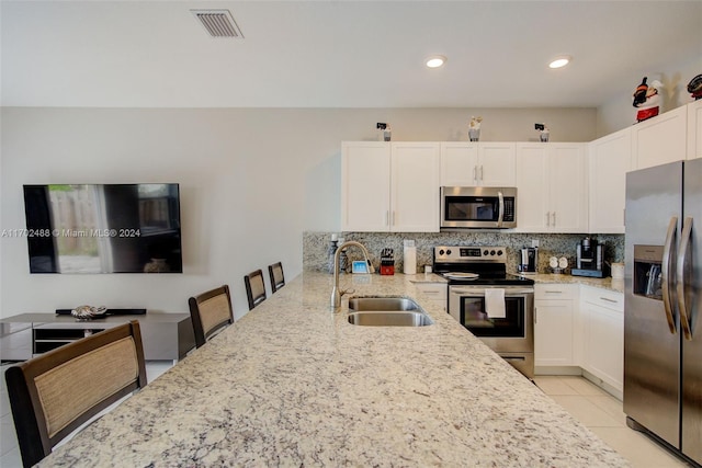 kitchen with white cabinets, stainless steel appliances, light stone countertops, and sink