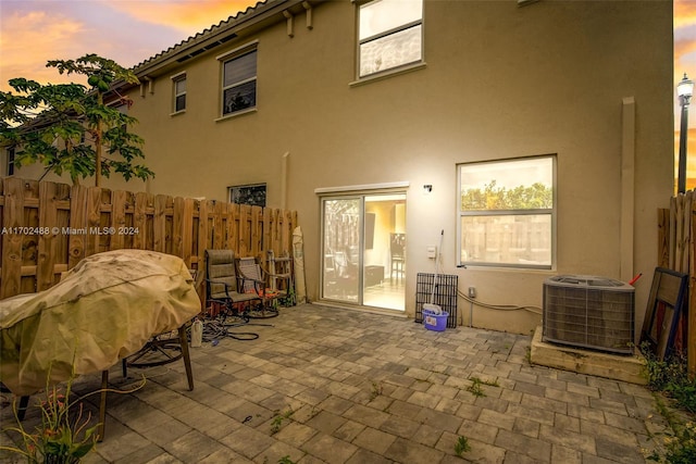 back house at dusk featuring a patio area and central AC unit