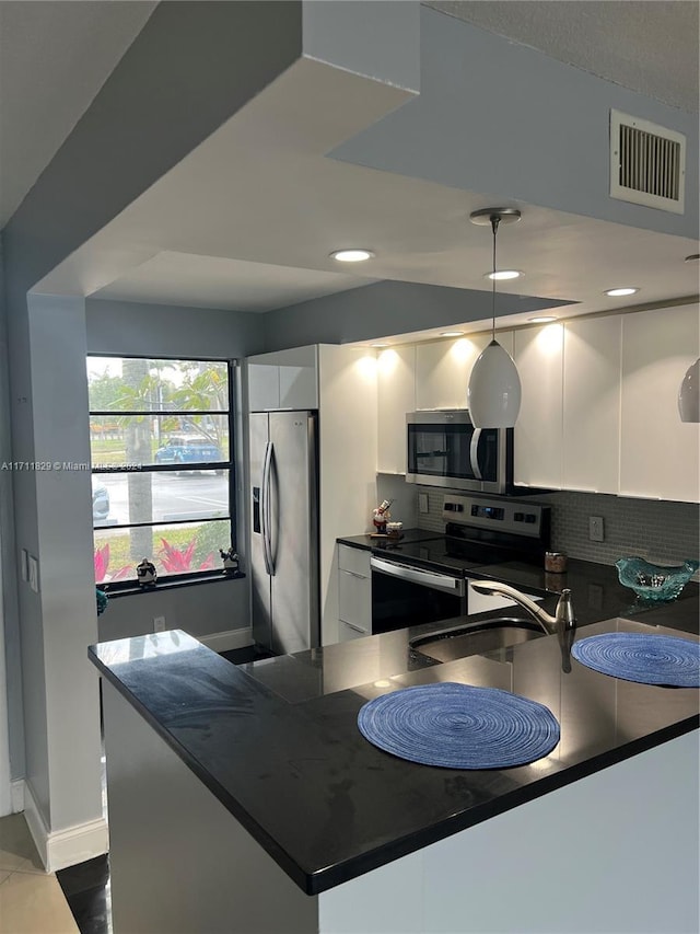 kitchen featuring white cabinets, sink, tasteful backsplash, decorative light fixtures, and stainless steel appliances