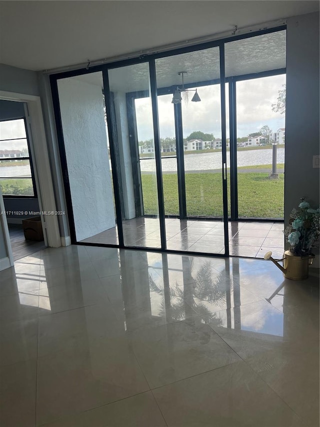 doorway with a wall of windows and light tile patterned flooring