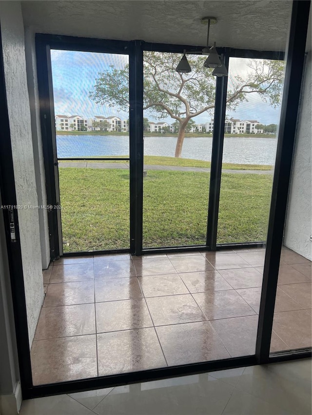 doorway to outside featuring a water view, light tile patterned flooring, and a wall of windows