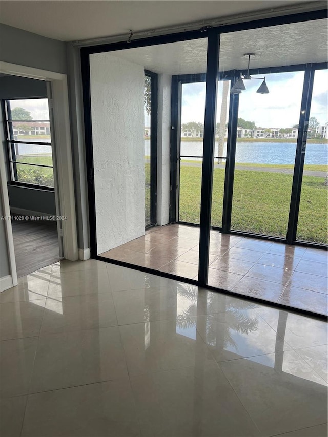 doorway with floor to ceiling windows, a water view, and light tile patterned floors