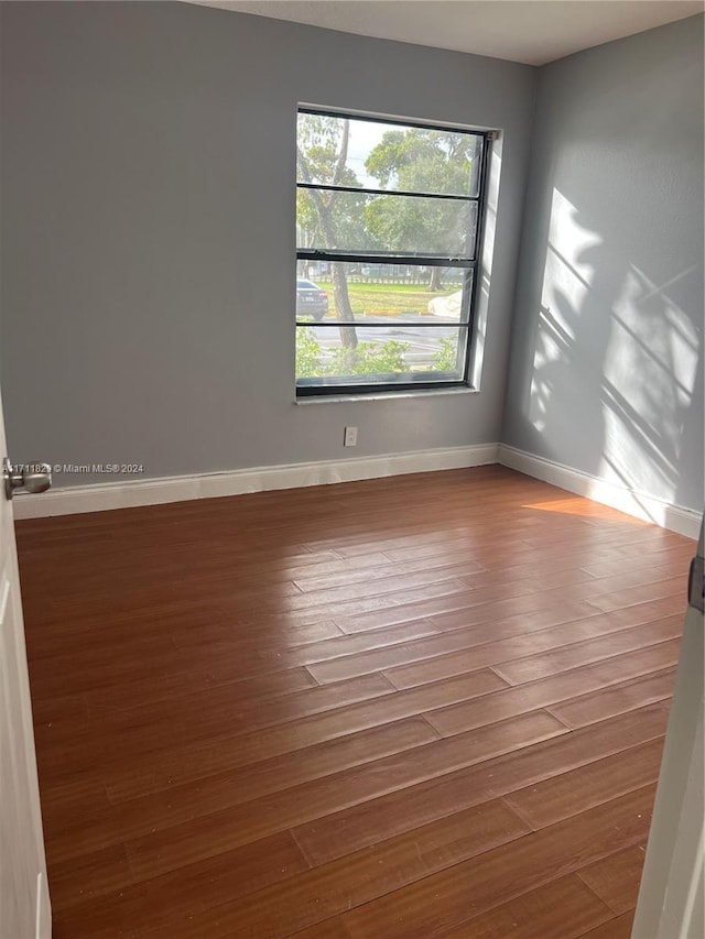 empty room with hardwood / wood-style flooring and a healthy amount of sunlight