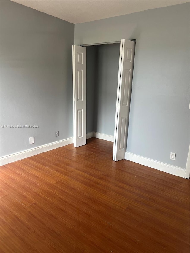 unfurnished bedroom with a closet and dark wood-type flooring