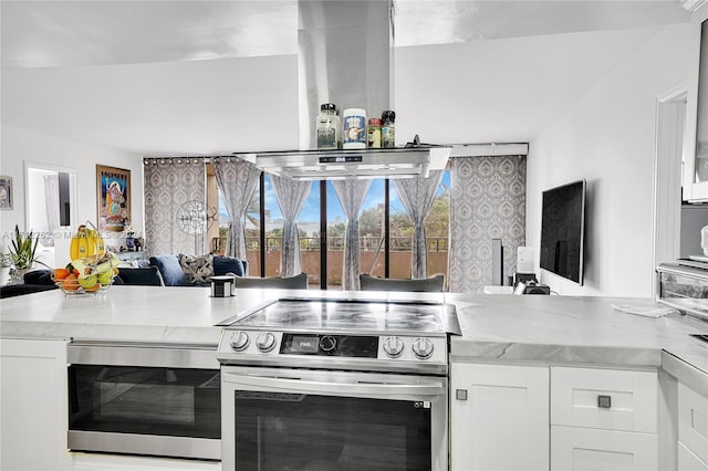 kitchen with kitchen peninsula, white cabinetry, light stone counters, and appliances with stainless steel finishes