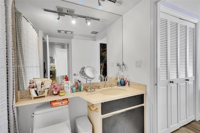 bathroom with vanity, track lighting, toilet, and hardwood / wood-style flooring