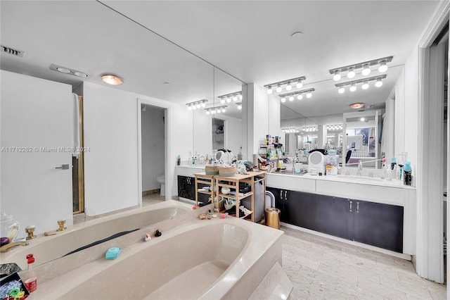 bathroom featuring vanity, a bath, and toilet