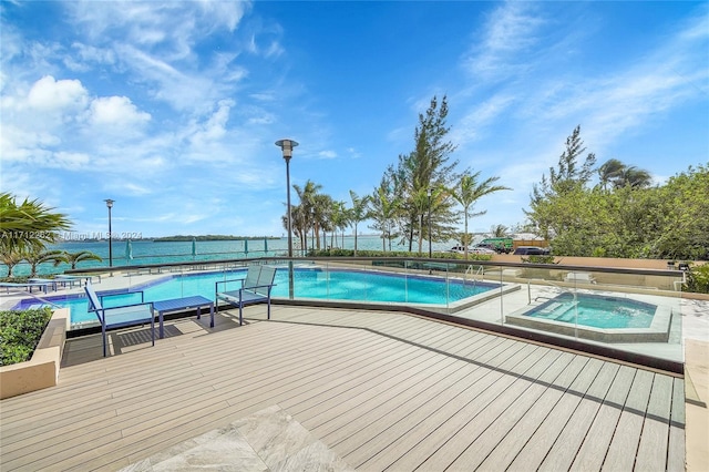 view of swimming pool featuring a deck with water view and a hot tub