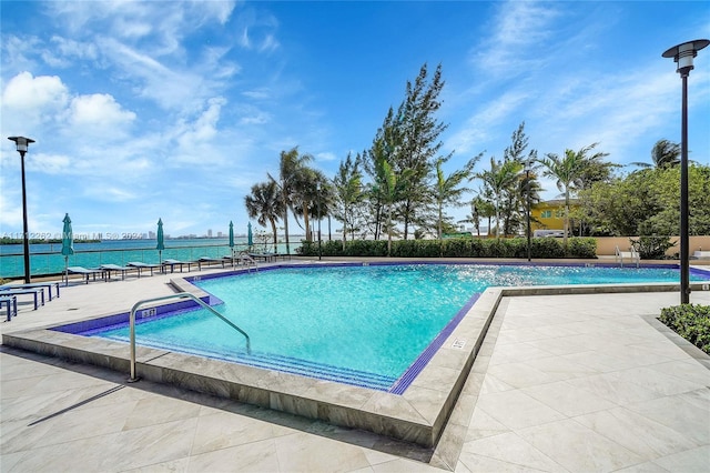 view of swimming pool with a water view and a patio area