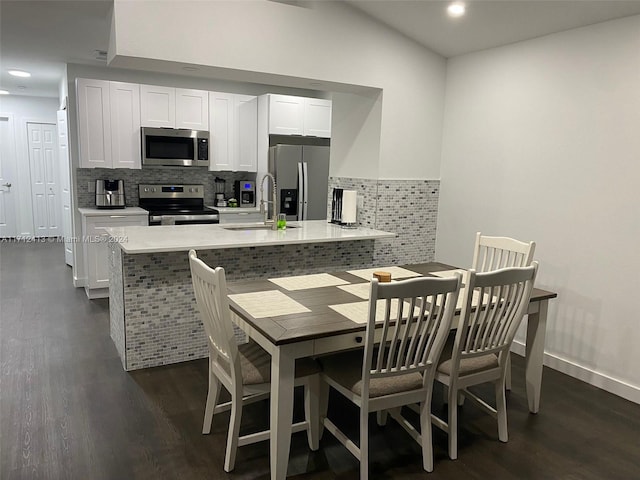 kitchen featuring white cabinetry, tasteful backsplash, dark hardwood / wood-style flooring, kitchen peninsula, and appliances with stainless steel finishes