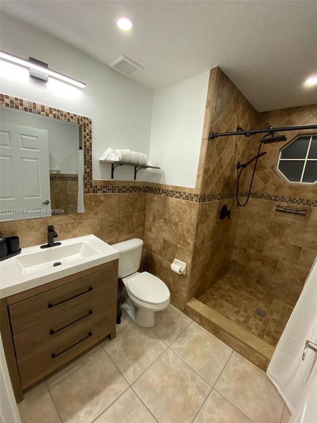 bathroom with vanity, tile patterned floors, toilet, tile walls, and a tile shower