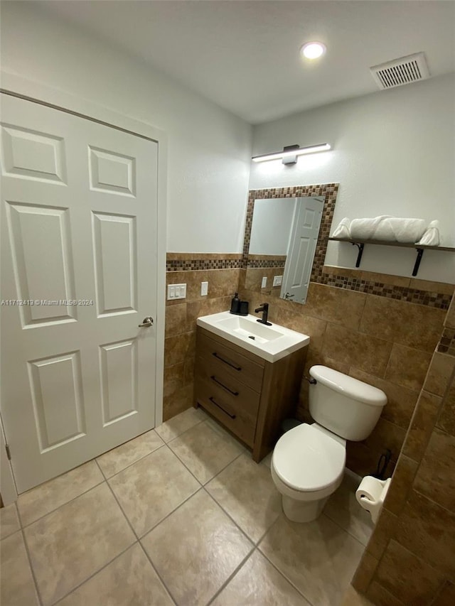 bathroom with tile patterned flooring, vanity, toilet, and tile walls