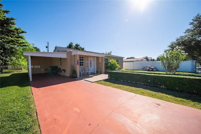 back of property with a carport and a lawn