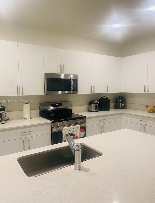 kitchen with sink, white cabinets, and appliances with stainless steel finishes