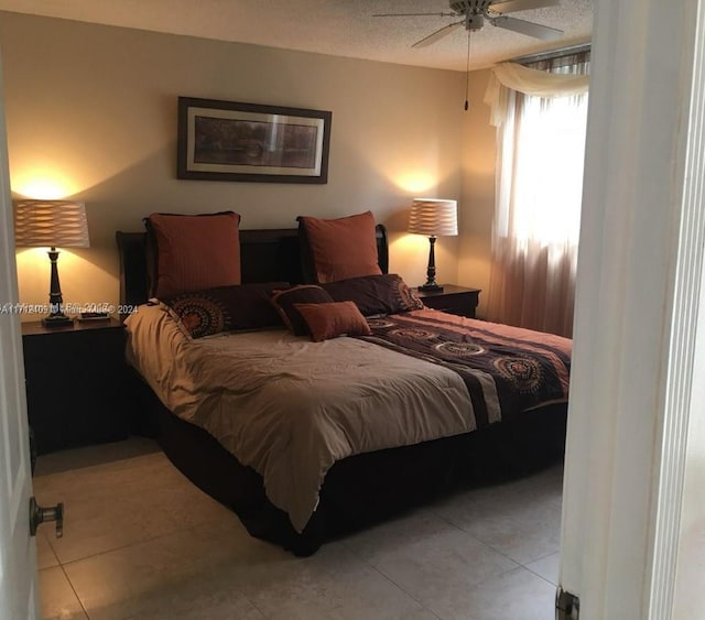 tiled bedroom with ceiling fan and a textured ceiling