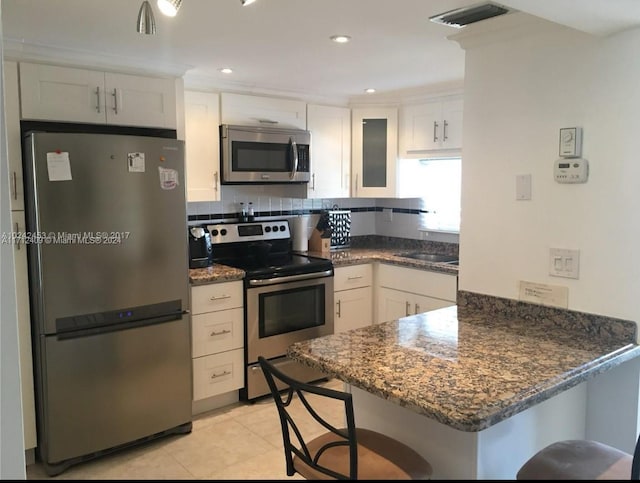 311 S Hollybrook Dr Unit 202, Pembroke Pines, FL 33025 - kitchen with kitchen peninsula, dark stone counters, a kitchen bar, white cabinets, and appliances with stainless steel finishes
