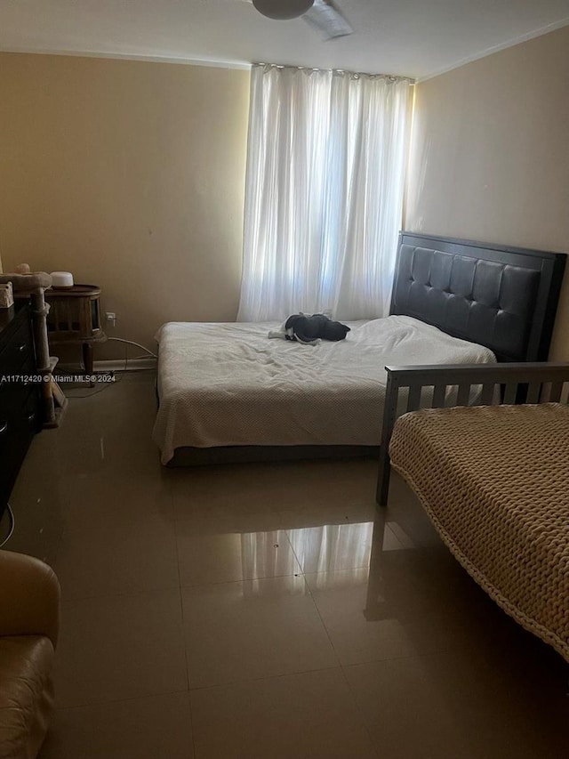 tiled bedroom featuring ceiling fan and crown molding