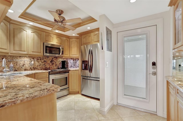 kitchen with light tile patterned floors, a sink, appliances with stainless steel finishes, backsplash, and light stone counters