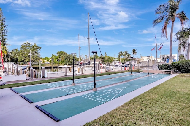 view of property's community featuring a yard, fence, and shuffleboard