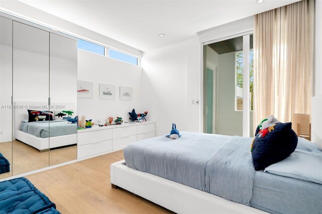 bedroom with hardwood / wood-style floors, a closet, and multiple windows