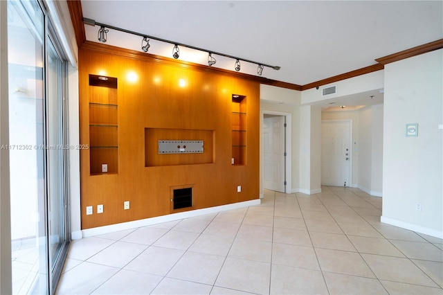 tiled empty room featuring built in shelves and ornamental molding