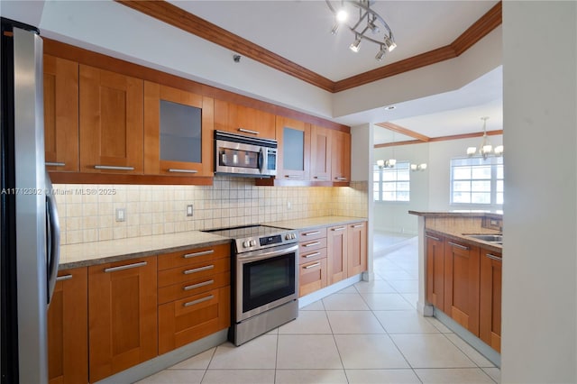 kitchen featuring light stone counters, appliances with stainless steel finishes, crown molding, and hanging light fixtures