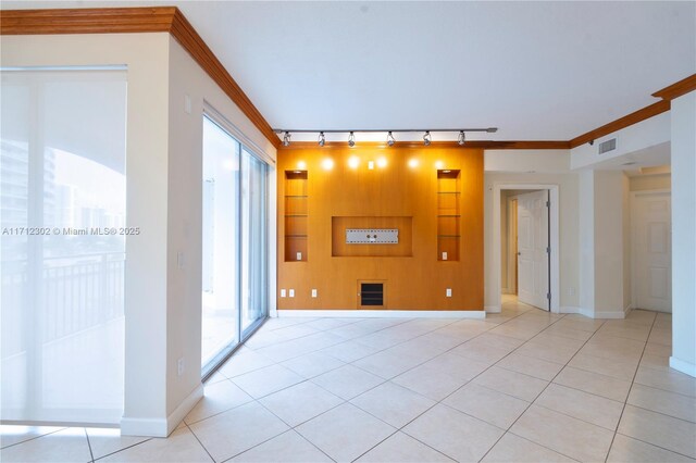 tiled empty room featuring crown molding and track lighting