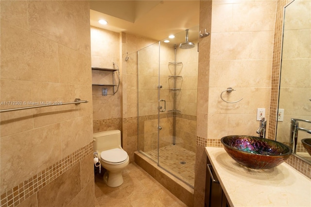 bathroom with tile walls, tile patterned flooring, vanity, an enclosed shower, and toilet