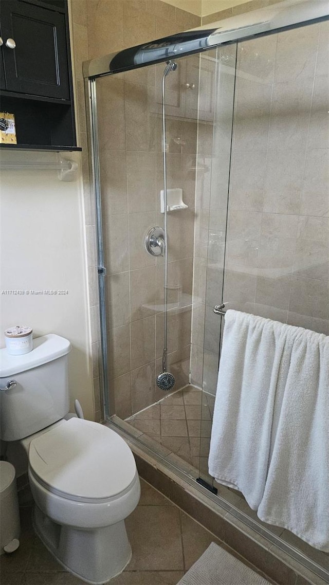 bathroom with tile patterned floors, toilet, and an enclosed shower