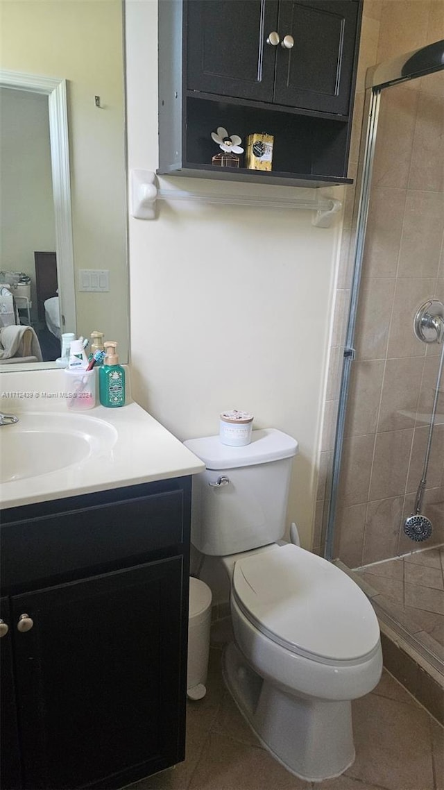 bathroom featuring tile patterned flooring, vanity, a shower with shower door, and toilet