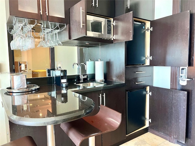 kitchen with light tile patterned flooring, dark brown cabinets, and sink