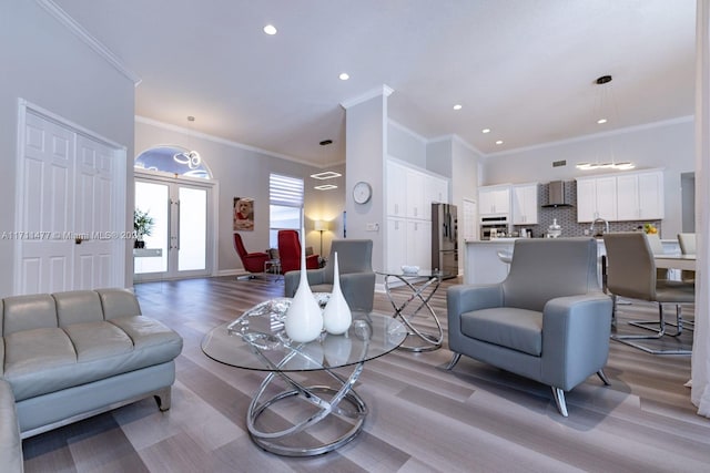 living room featuring crown molding, french doors, and light wood-type flooring