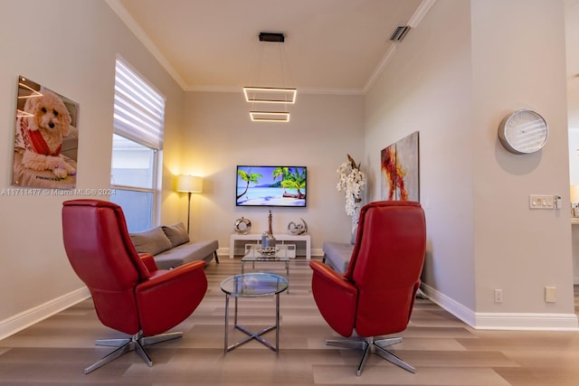 sitting room with hardwood / wood-style flooring and ornamental molding