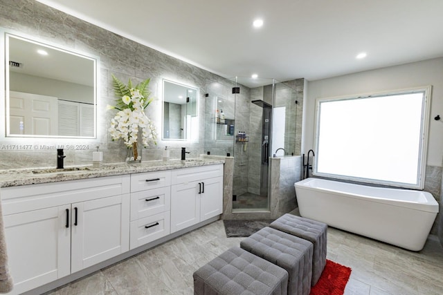 bathroom featuring vanity, independent shower and bath, and tile walls