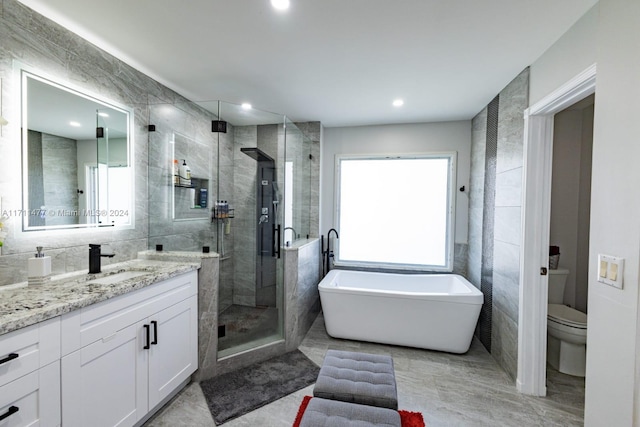 full bathroom with vanity, a healthy amount of sunlight, and tile walls