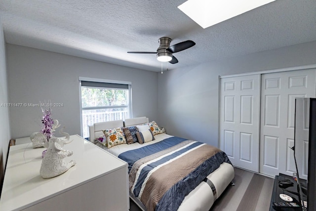 bedroom with a textured ceiling, dark hardwood / wood-style flooring, a closet, and ceiling fan