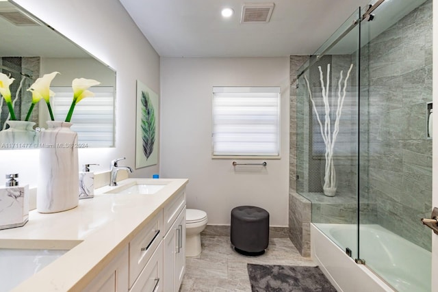 full bathroom featuring vanity, bath / shower combo with glass door, and toilet