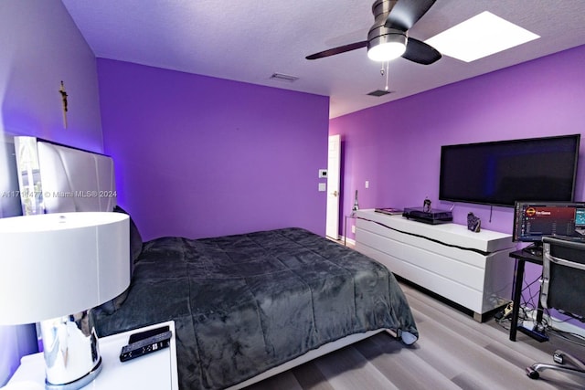 bedroom with ceiling fan, light hardwood / wood-style flooring, and a textured ceiling