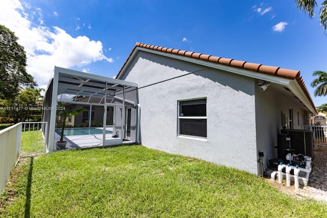 rear view of property featuring a lanai and a lawn