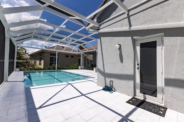 view of swimming pool featuring glass enclosure and a patio