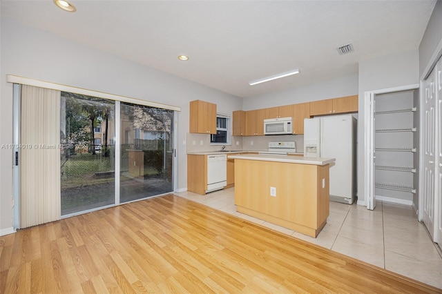 kitchen with light hardwood / wood-style floors, a kitchen island, white appliances, and sink