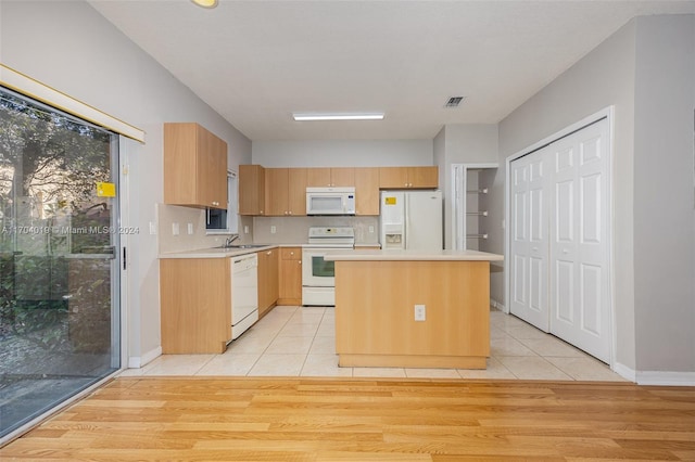 kitchen with light hardwood / wood-style floors, a kitchen island, white appliances, and sink