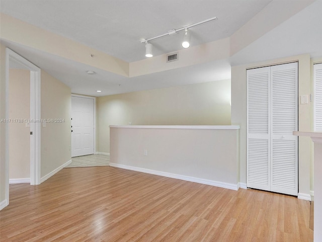 empty room featuring light wood-type flooring and track lighting