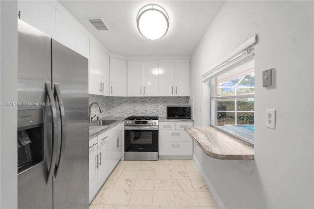 kitchen with decorative backsplash, sink, white cabinetry, and appliances with stainless steel finishes