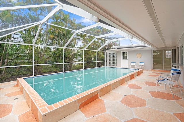 view of swimming pool with glass enclosure and a patio