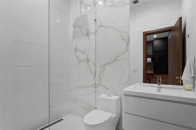 bathroom featuring tiled shower, vanity, and toilet