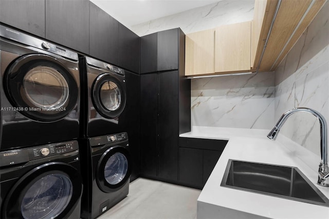 washroom with sink, cabinets, and stacked washer / dryer