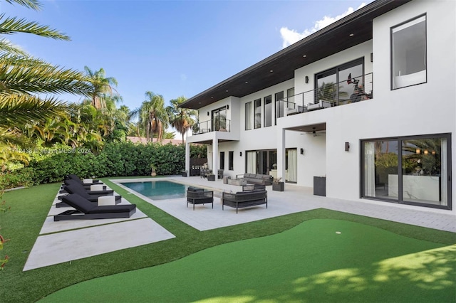 back of property with an outdoor living space, a patio area, and a balcony