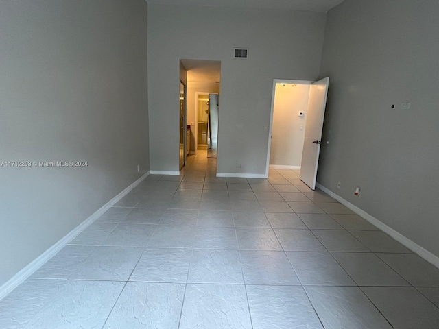 empty room featuring light tile patterned floors and a high ceiling